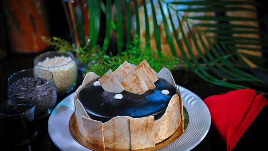 A cake placed on a plate alongside two glasses of drinks at Clarks Varanasi.