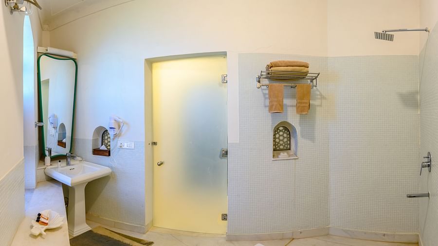 Bathroom with sink, mirror, shower, towel rack, small arched alcove, and tiled floor - Tijara Fort-Palace - 19th Century, Alwar.