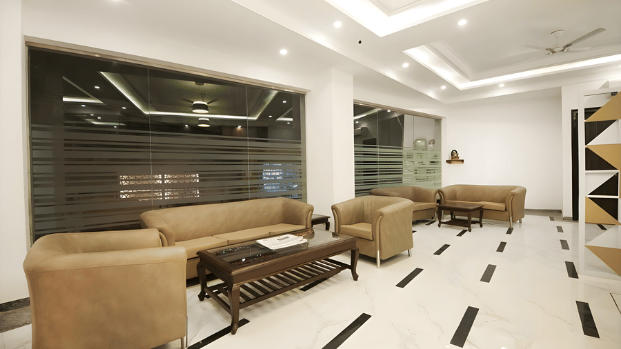 The main lobby seating area at Hotel Apple Park Delhi, showing tan leather armchairs and sofas arranged around low coffee tables on a polished floor.