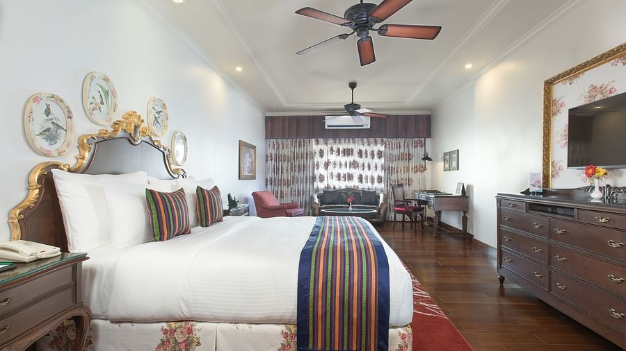 a plush bed facing the TV and a wooden cabinet - Mayfair Himalayan Spa Resort Kalimpong