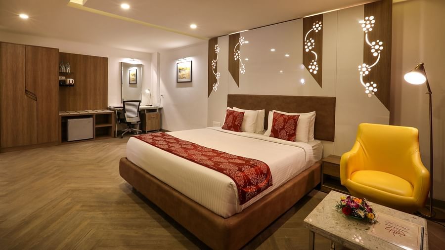 Stylish hotel bedroom with double bed and yellow armchair  | Mango Hill Central, Chennai