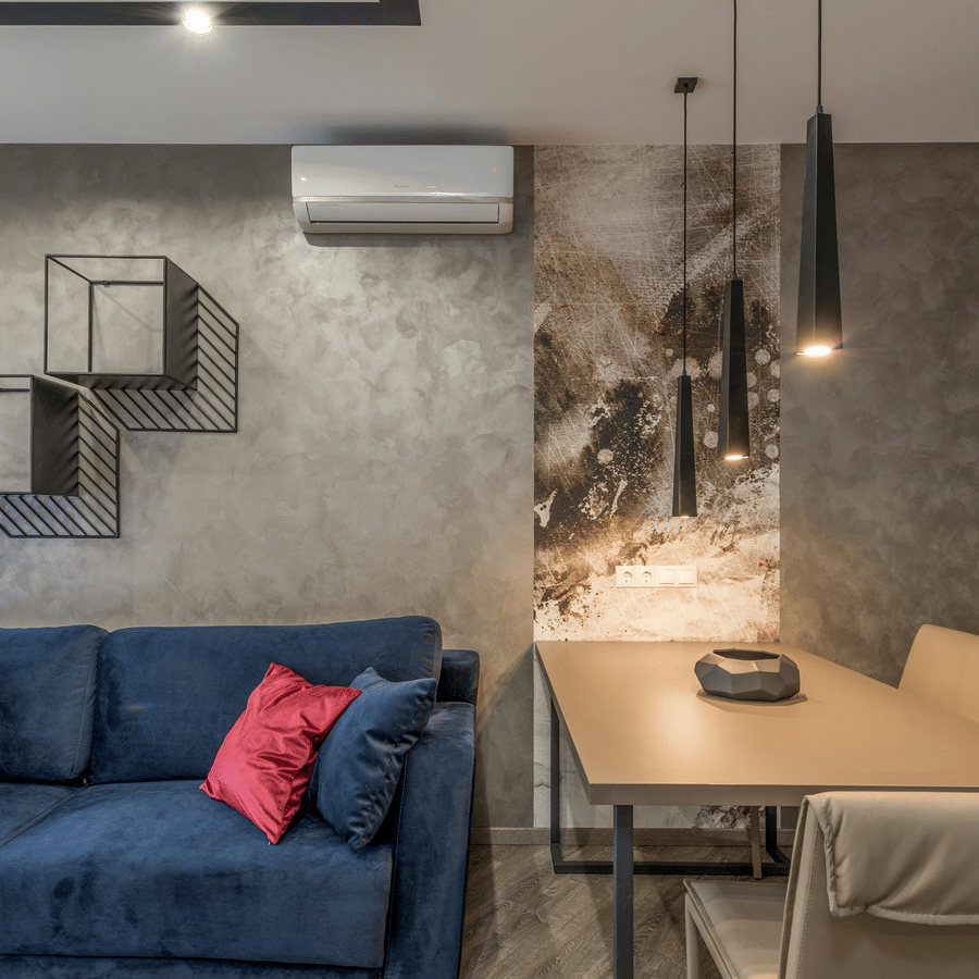 Modern suite living area with blue sofa, dining table, pendant lights, wall art, and contemporary decor.