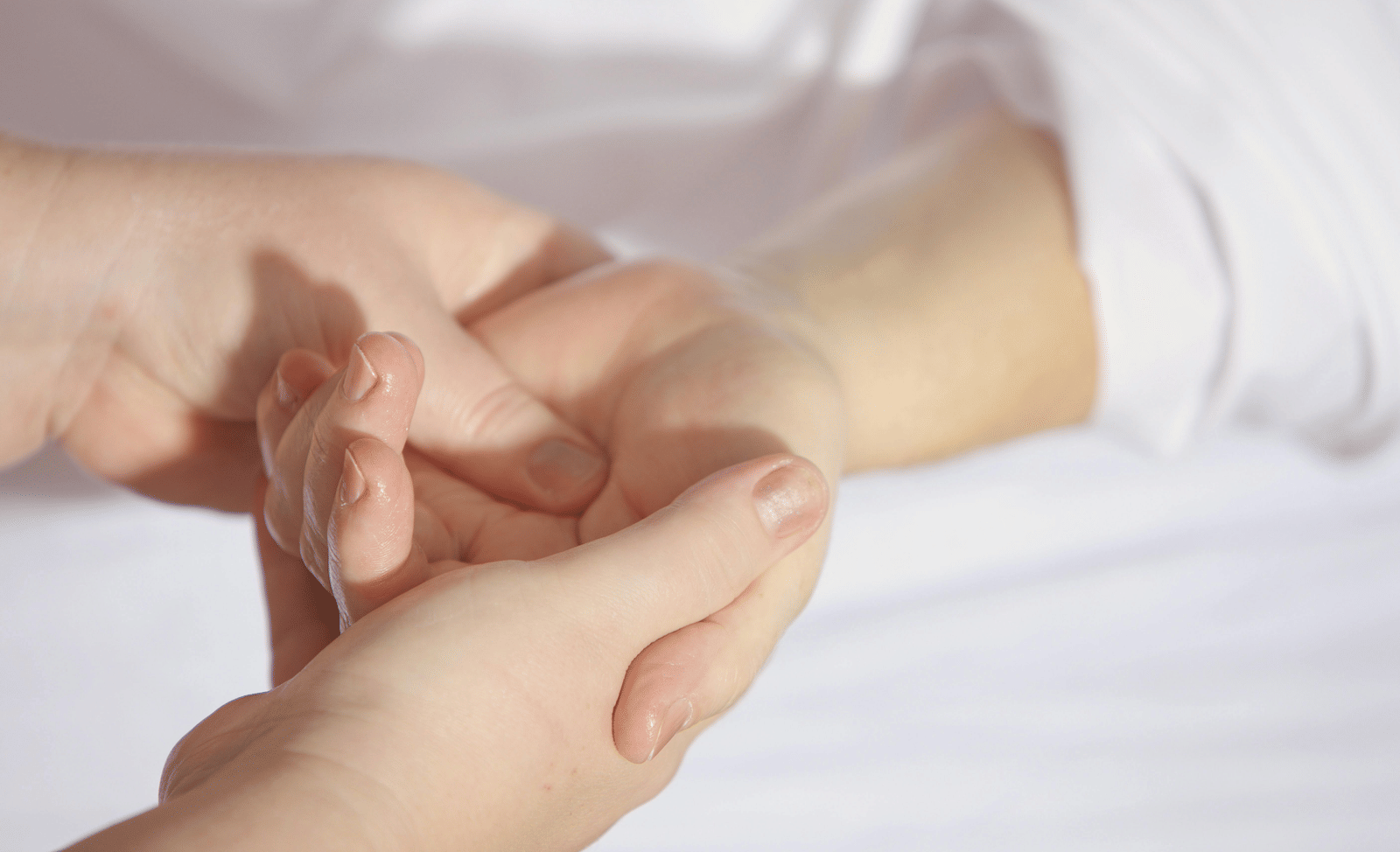 A close-up of a person's hands gently massaging another person's wrist.