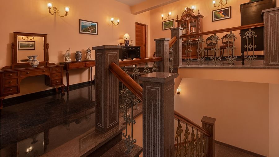 A staircase with wall-mounted lamps and paintings leading to the next floor - Highland Sarovar Portico, Sindhudurg