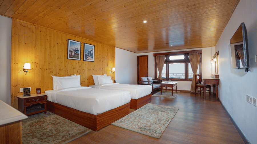 A bedroom at Summit Norbu Ghang - The Signature Collection, Gangtok, 2 single beds, sofa, bedside tables, rug, and work desk.
