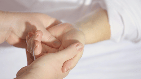 A close-up of a person's hands gently massaging another person's wrist.