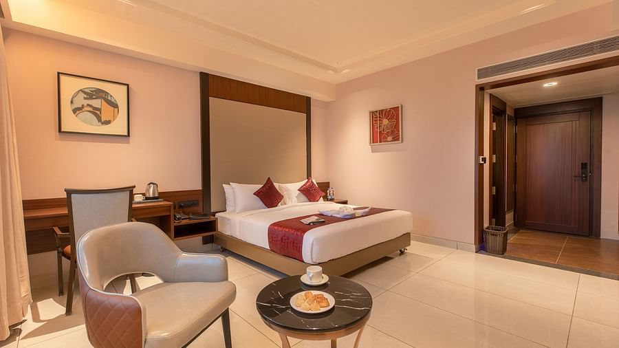 An image of a room featuring a bed, a study area beside it, and a chair with a table at M Pro Palace.