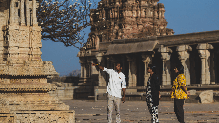 Tourists exploring ancient temple ruins near Evolve Back Hampi