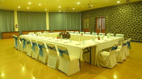 An image of the meeting hall with seating arrangement, bright lighting, and the amenities required for meetings - Great Trails Yercaud by GRT Hotels