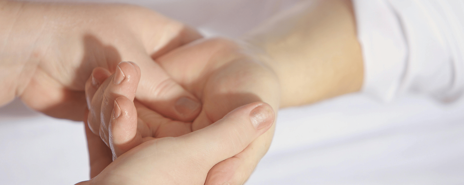 A close-up of a person's hands gently massaging another person's wrist.