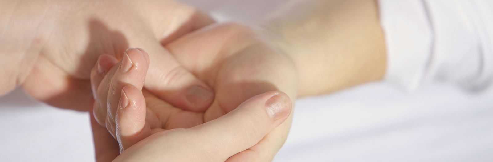 A close-up shot of a hand receiving a therapeutic hand massage from a masseuse.