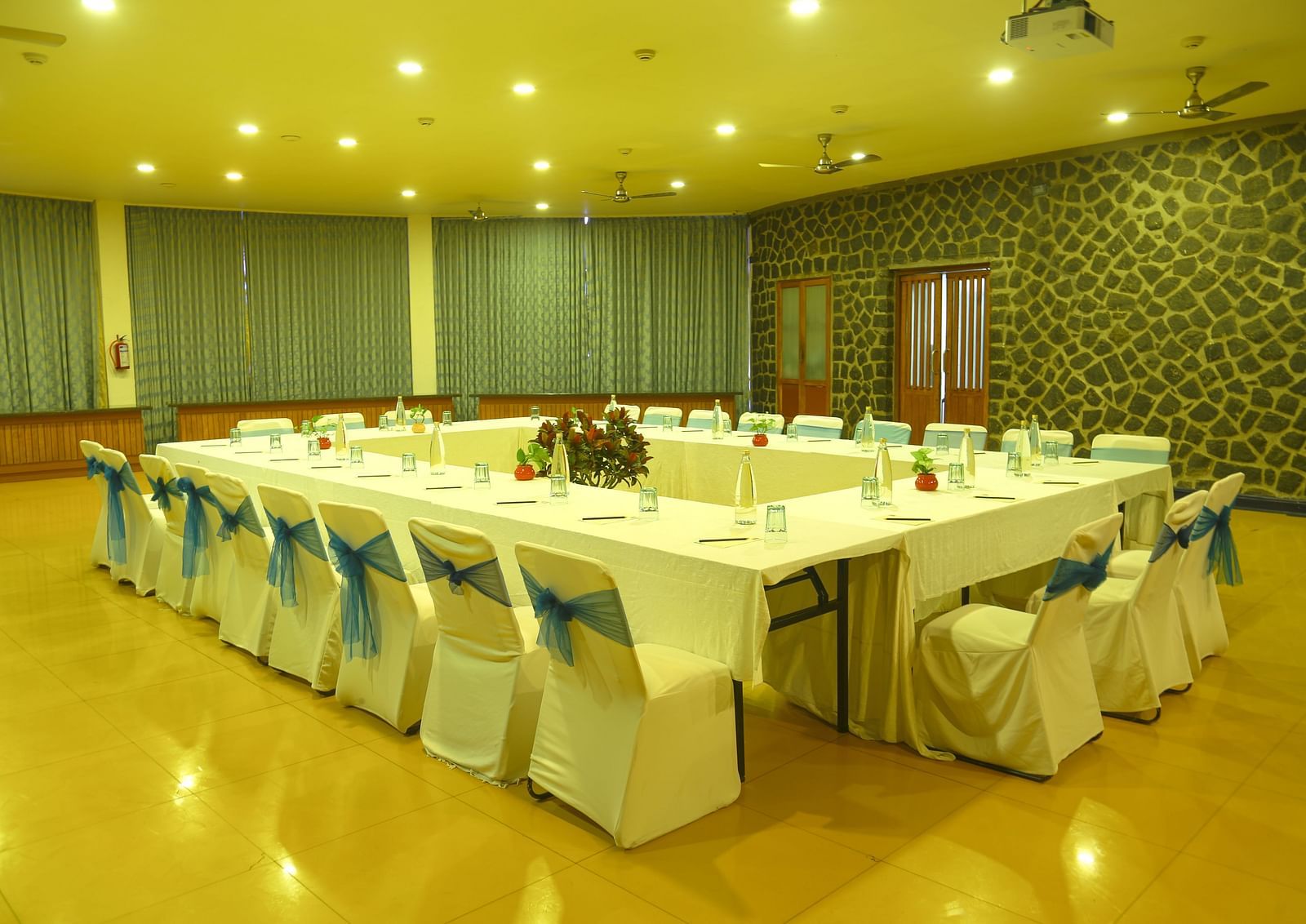 An image of the meeting hall with seating arrangement, bright lighting, and the amenities required for meetings - Great Trails Yercaud by GRT Hotels