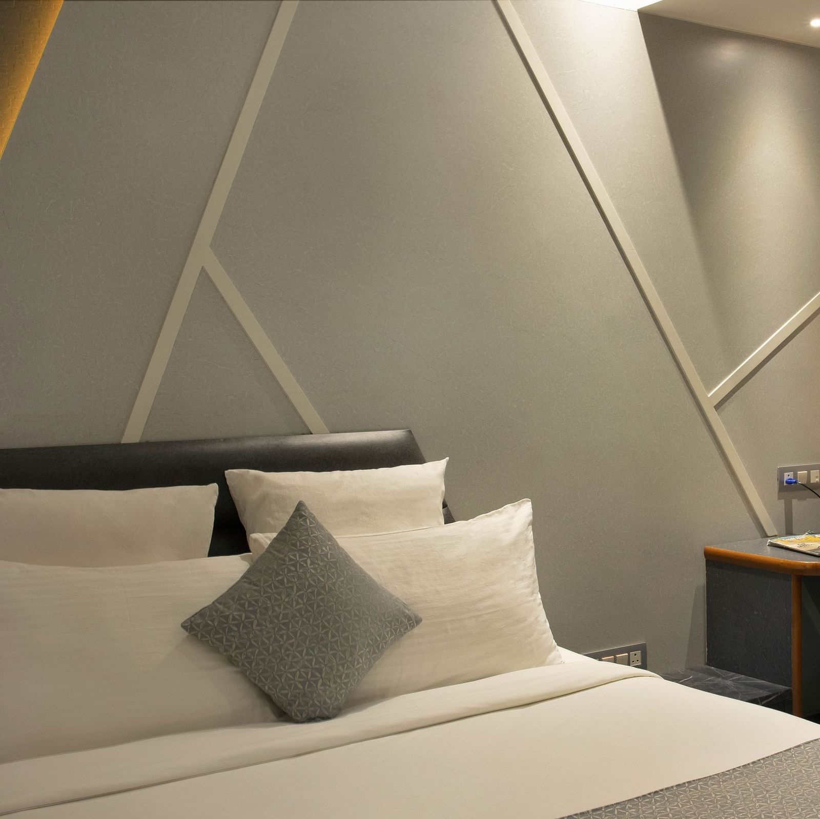 angular shot of Coral Deluxe Room at Coral Reef Hotel and Spa in Port Blair featuring a plush bed next to which a work desk and chair is placed near the window