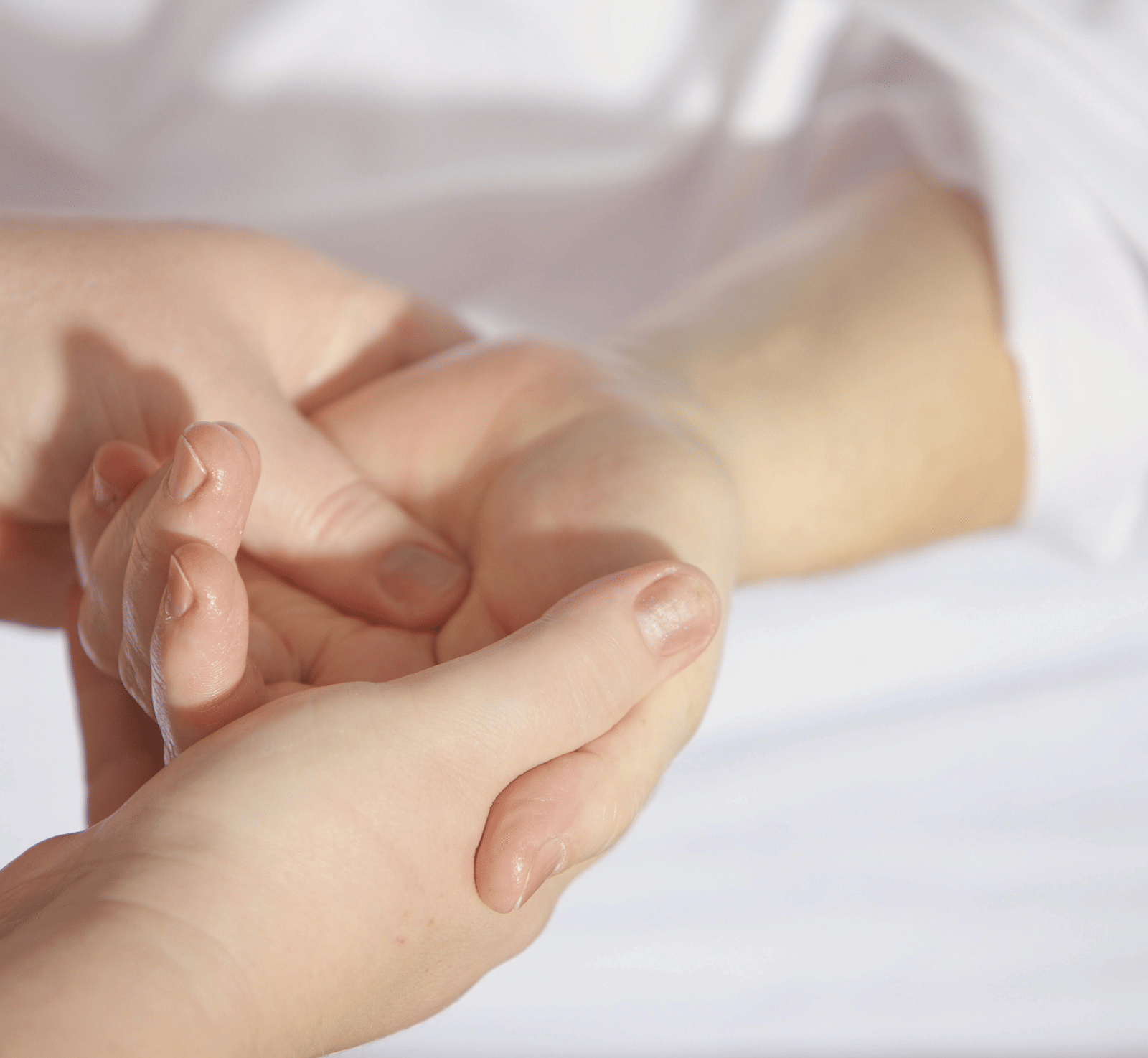 A close-up of a person's hands gently massaging another person's wrist.