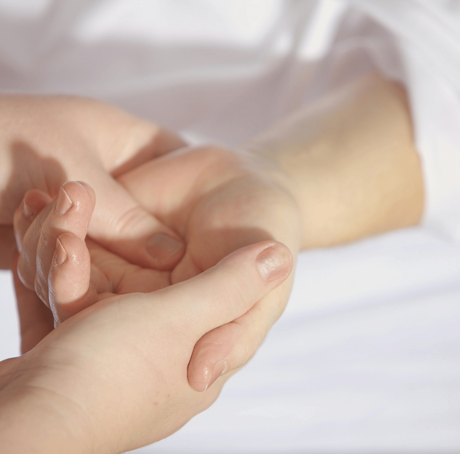 A close-up of a person's hands gently massaging another person's wrist.