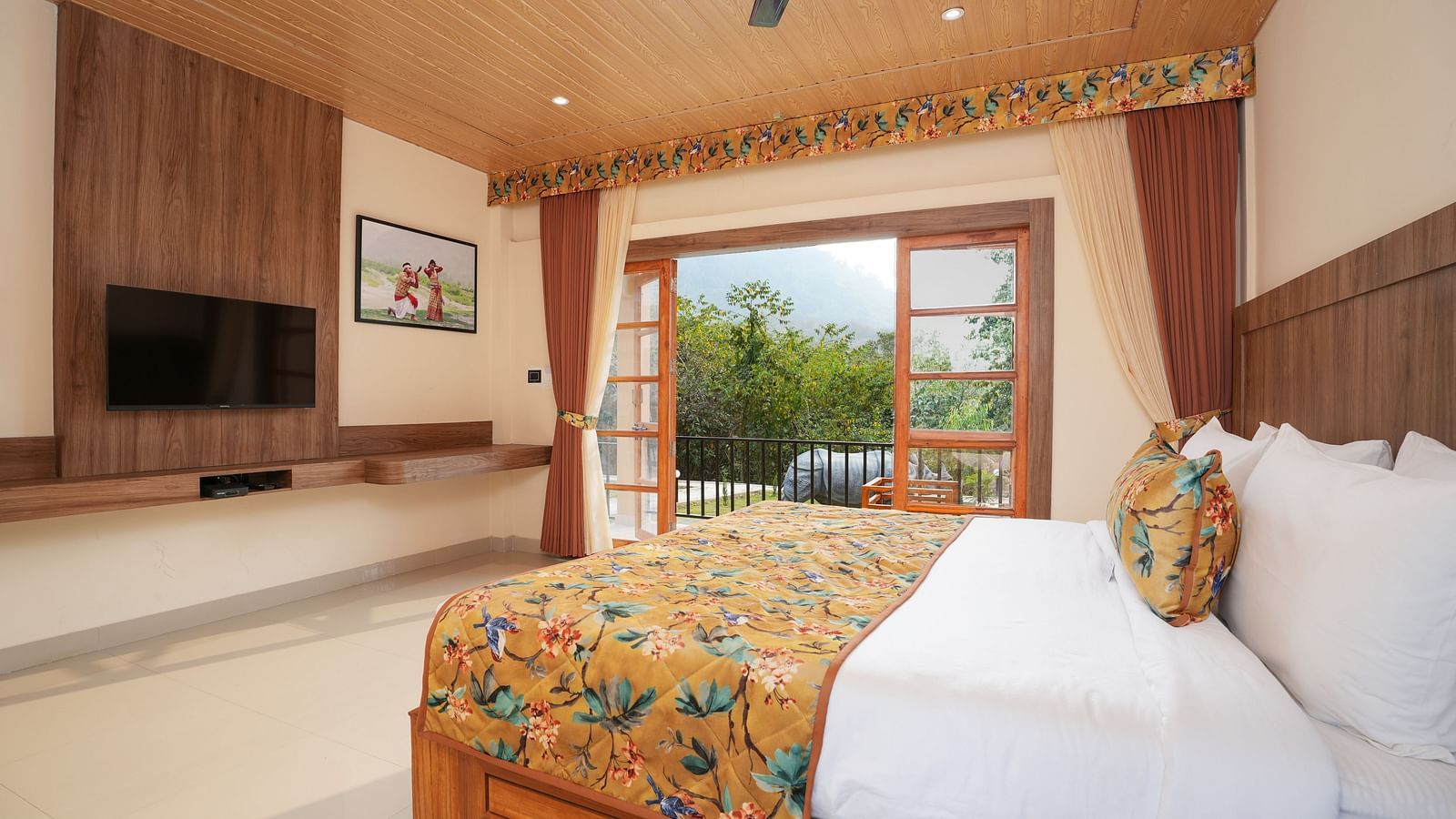 Bungalow featuring a spacious bed with a wall-mounted television and a large balcony at Summit Green Lake Tea Resort & Spa, Kaziranga