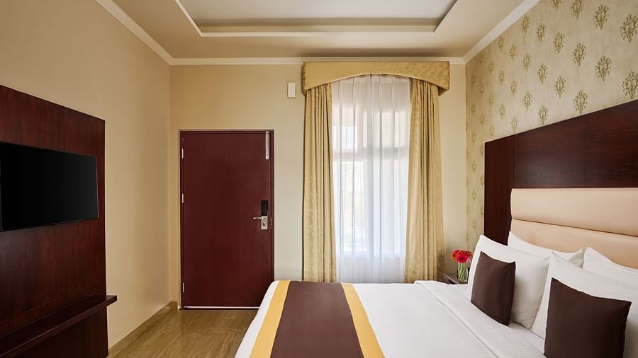  the door, television, double bed and floor-to-ceiling windows in the DELUXE ROOM - Royal Kingdom Sarovar Portico, Pilibhit