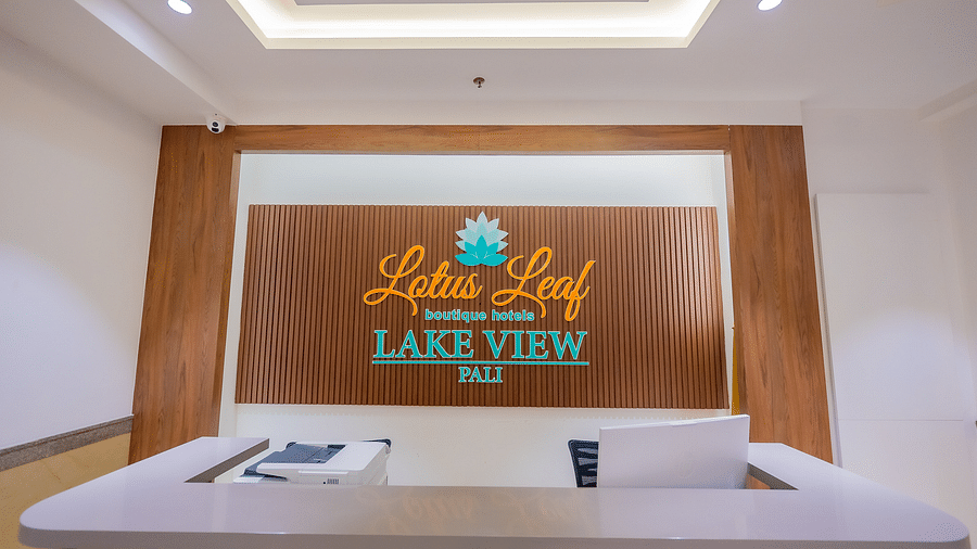 Hotel reception desk with a brown wall that reads Lotus Leaf Boutique Hotels Lake View Pali