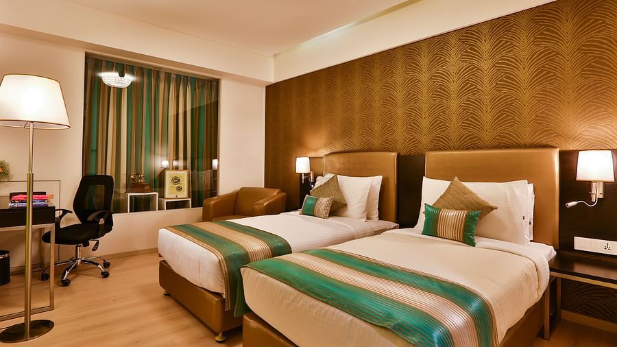 A room with twin beds, a standing desk and a work desk and chair at T24 Residency, Andheri East, Mumbai