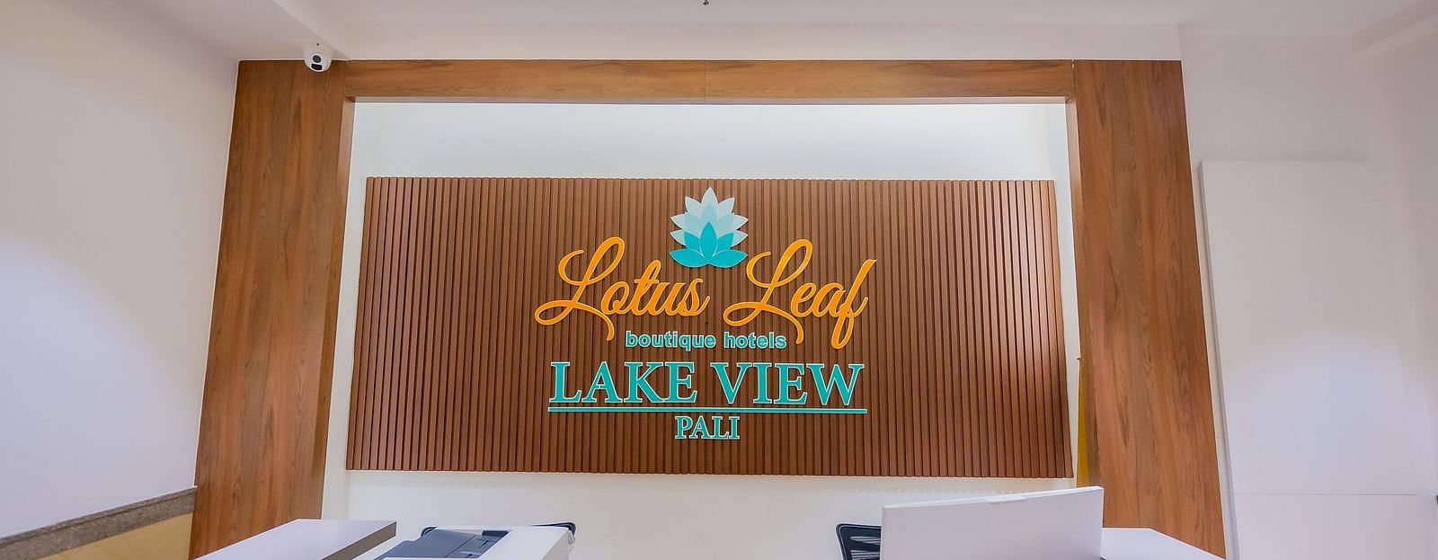Hotel reception desk with a brown wall that reads Lotus Leaf Boutique Hotels Lake View Pali