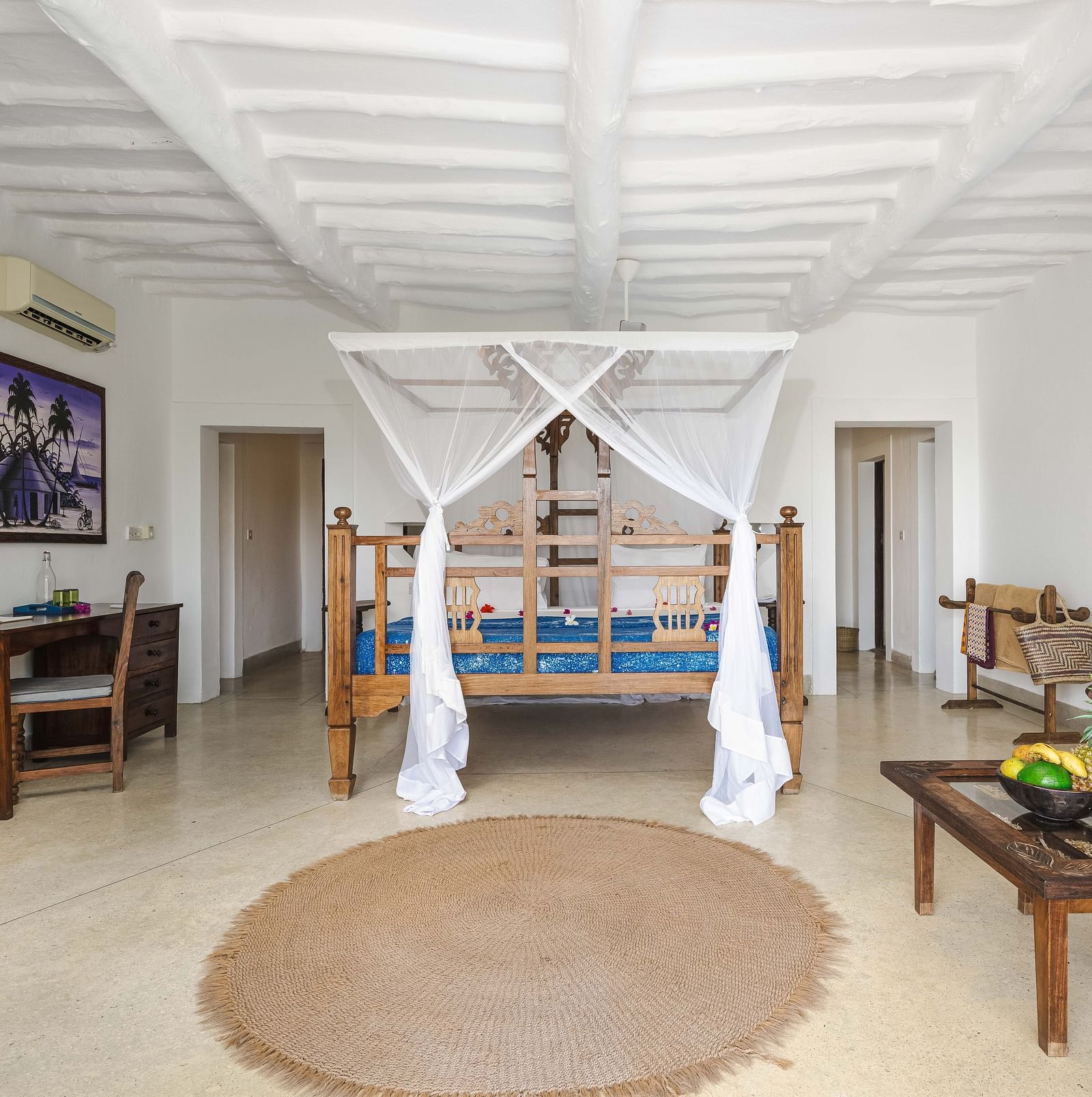 A bright hotel room with a wooden four-poster bed, a desk, and a seating area with wooden armchairs and a coffee table in Sea View Family Cottages - Shooting Star Boutique Hotel.