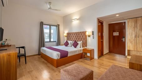 A hotel room with a bed, wooden flooring, and a desk – Monday Hotels HITEC City, Hyderabad
