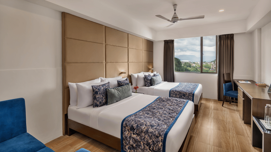 Guest room with twin beds and seating at Voyage Milestone Hotel and Banquet.