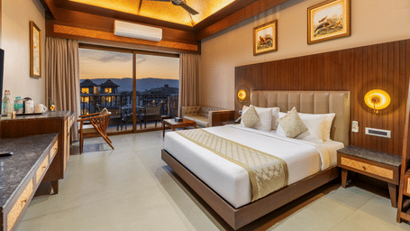 A premium resort suite showcases an inviting bed and warm wooden wall panelling under a stylish vaulted ceiling - Sajjan Bagh Resort and Spa, Kumbhalgarh