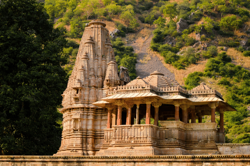 Sandstone shikhara temple set against an Aravalli hillside