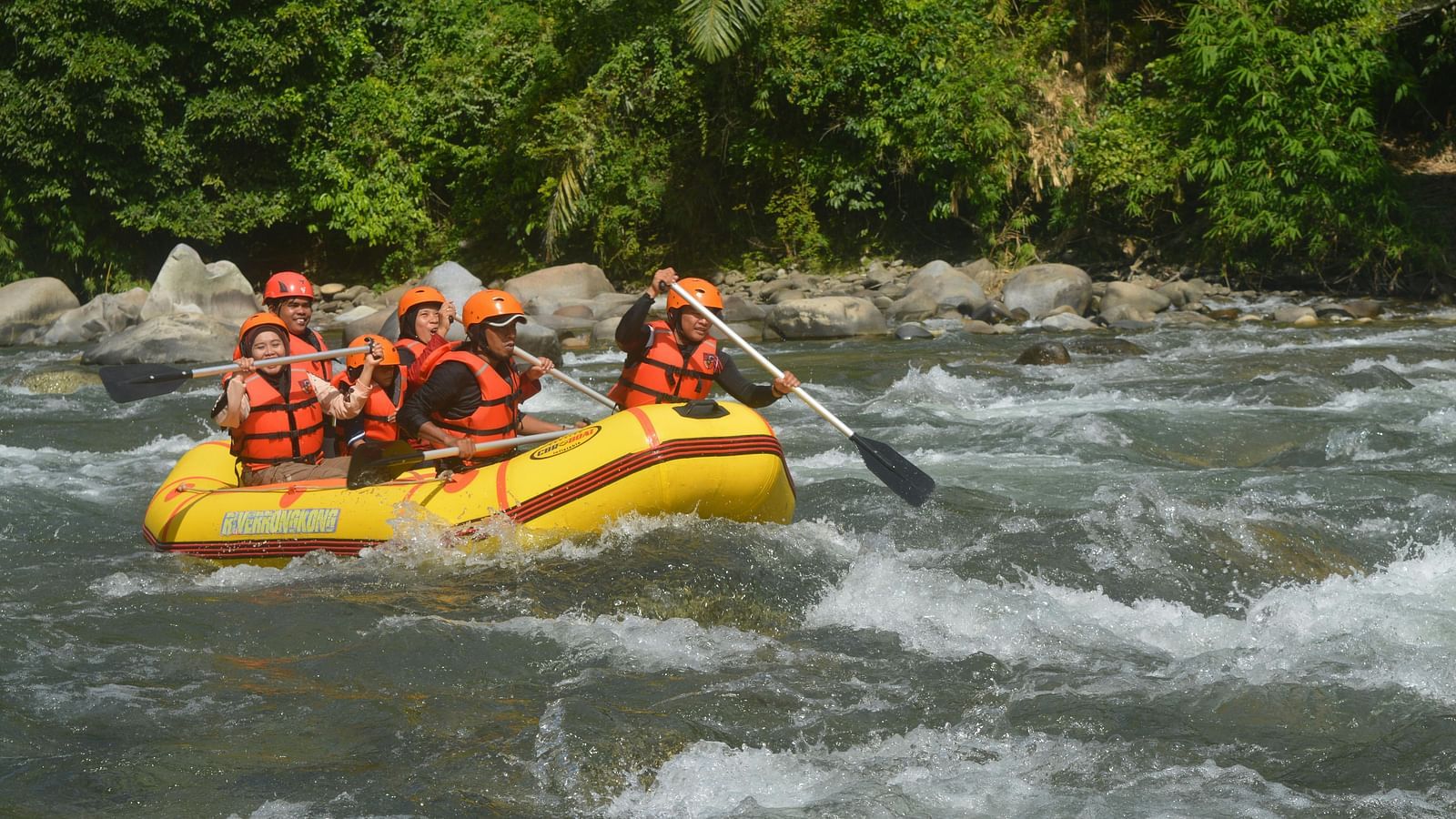 Group of people enjoying white-water rafting on a fast-flowing river.