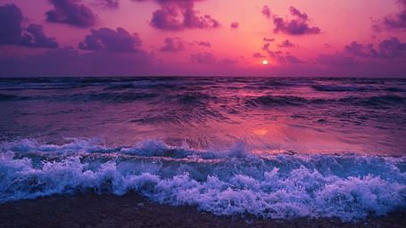 overview of a beach with water overlapping and Pretty pink hues on the sky