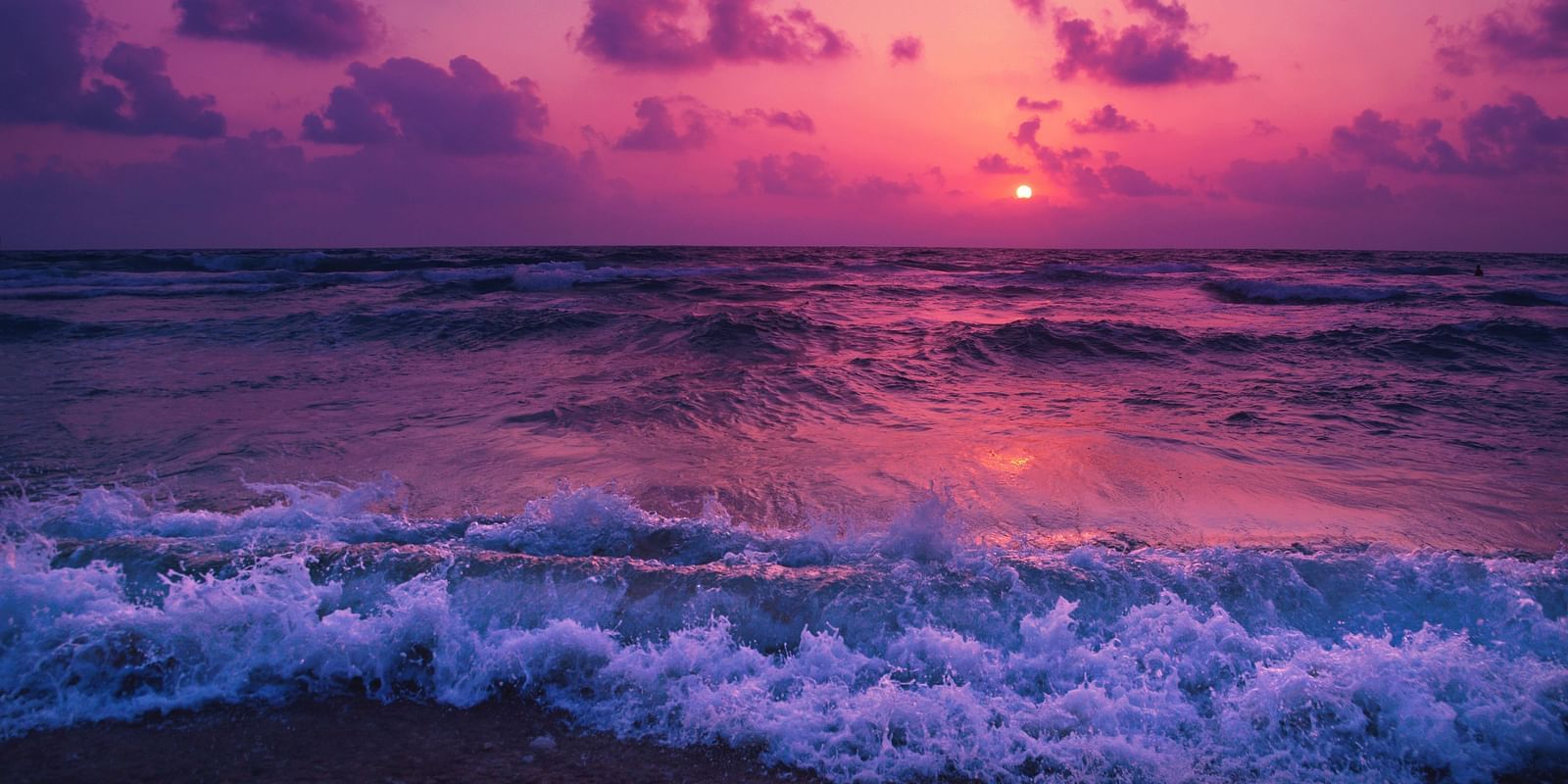 overview of a beach with water overlapping and Pretty pink hues on the sky
