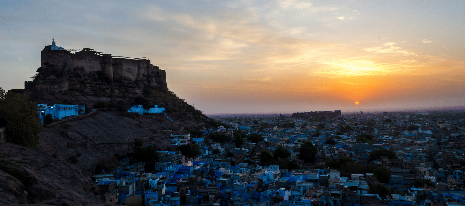 overhead view of Jodhpur at dusk, with the blue buildings around Mehrangarh Fort glowing in the the sunlight