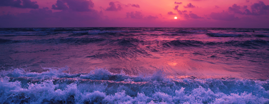 overview of a beach with water overlapping and Pretty pink hues on the sky