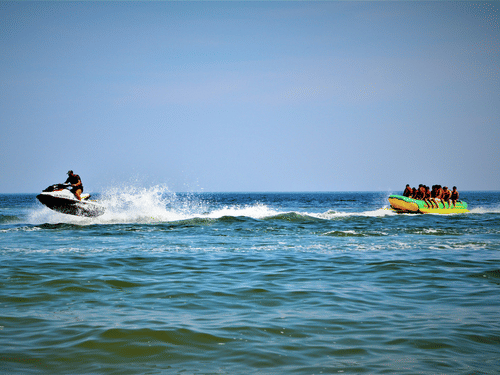 Visitors enjoying a banana boat ride while a jet ski speeds across the sea during an exciting water sports adventure.