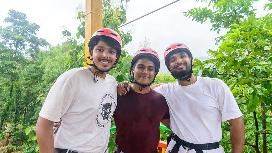 3 friends standing side by side happily, while wearing helmets and safety harnesses.