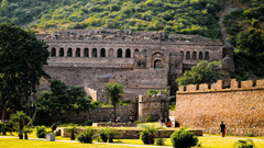 An overview of Bhangarh Fort with a manicured garden in front of it.