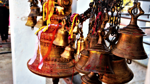 Temple bells hanging in a row, gently swaying with intricate designs.