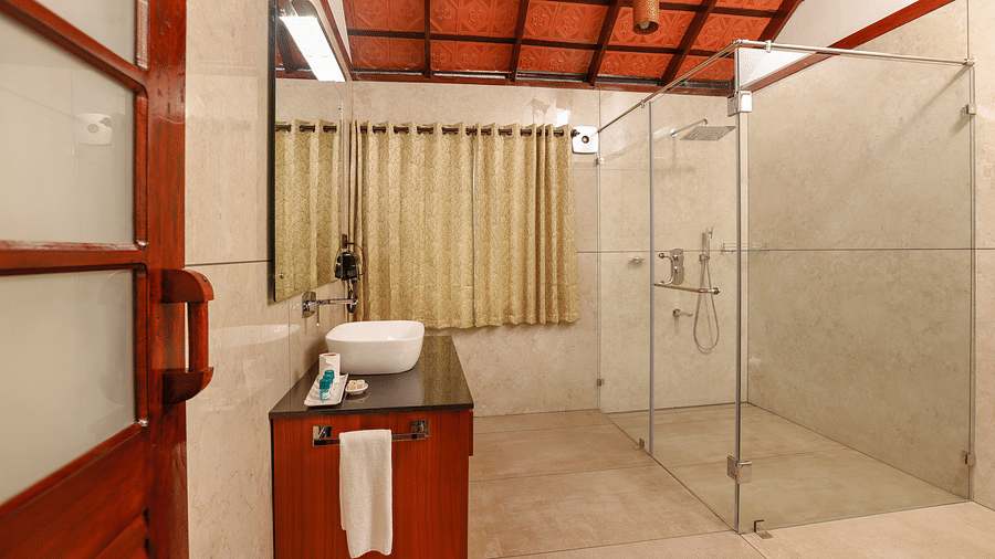 A side view of a bathroom that has a glass cubicle and vanity area | Vythiri Resort. Wayanad