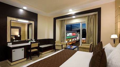 View of a Business Suite with a double bed facing a mirror and a work desk at Hotel Aadithya, Chennai