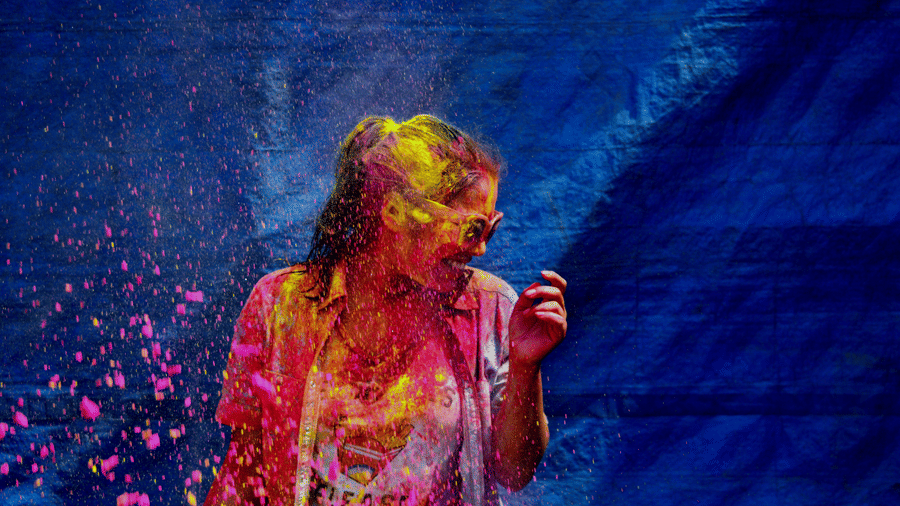 a girl covered in colour standing against blue backdrop