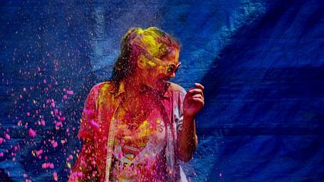 a girl covered in colour standing against blue backdrop