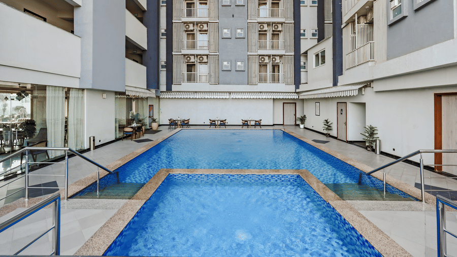 A swimming pool located in Urban Suites by BluSalzz, Jaipur, with buildings visible in the background.