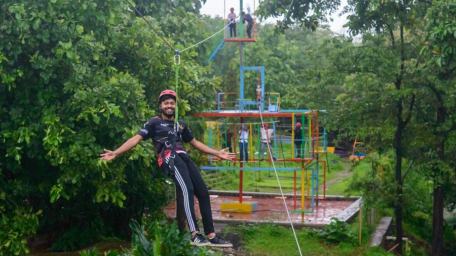 A cheerful man on a zipline, in the mddile of a forest