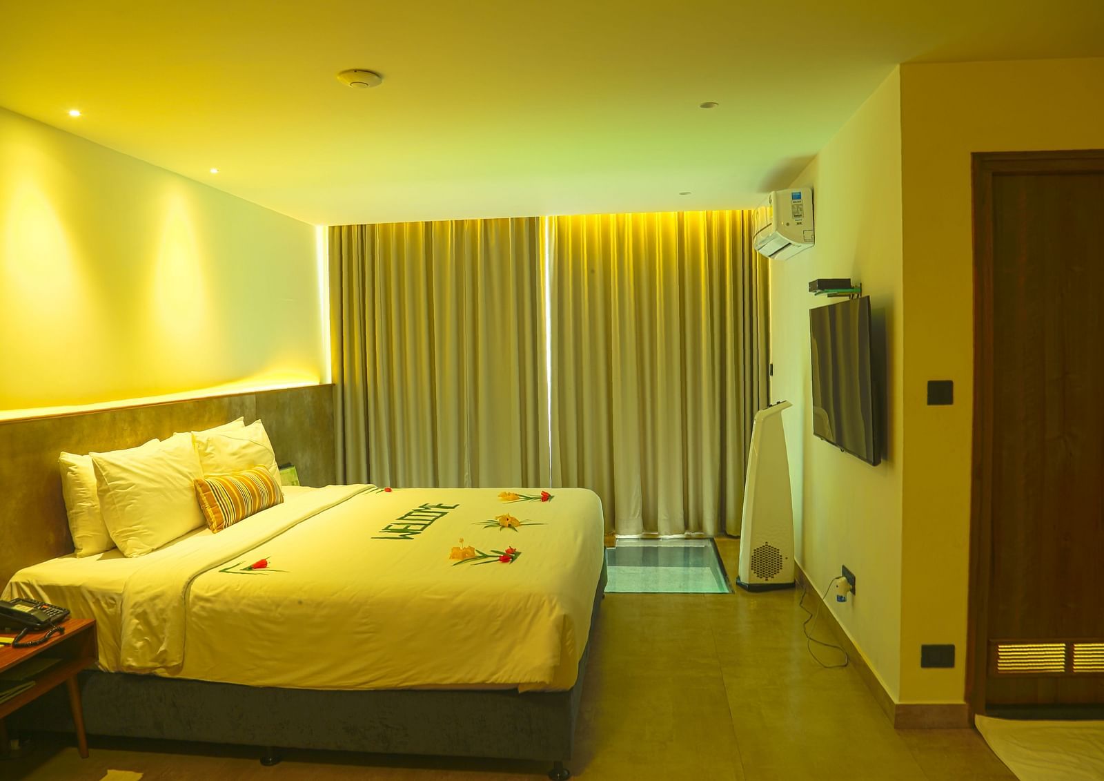 An image of a panorama view room with a king size bed, bed size table, flat screen TV with the curtains closed - Great Trails Yercaud by GRT Hotels