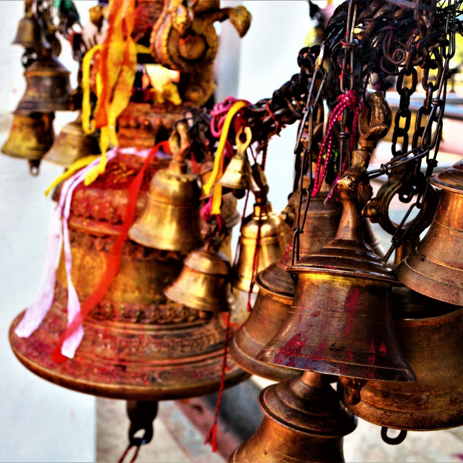 image featuring a cluster of bronze bells with red and yellow coloured threads tied over it