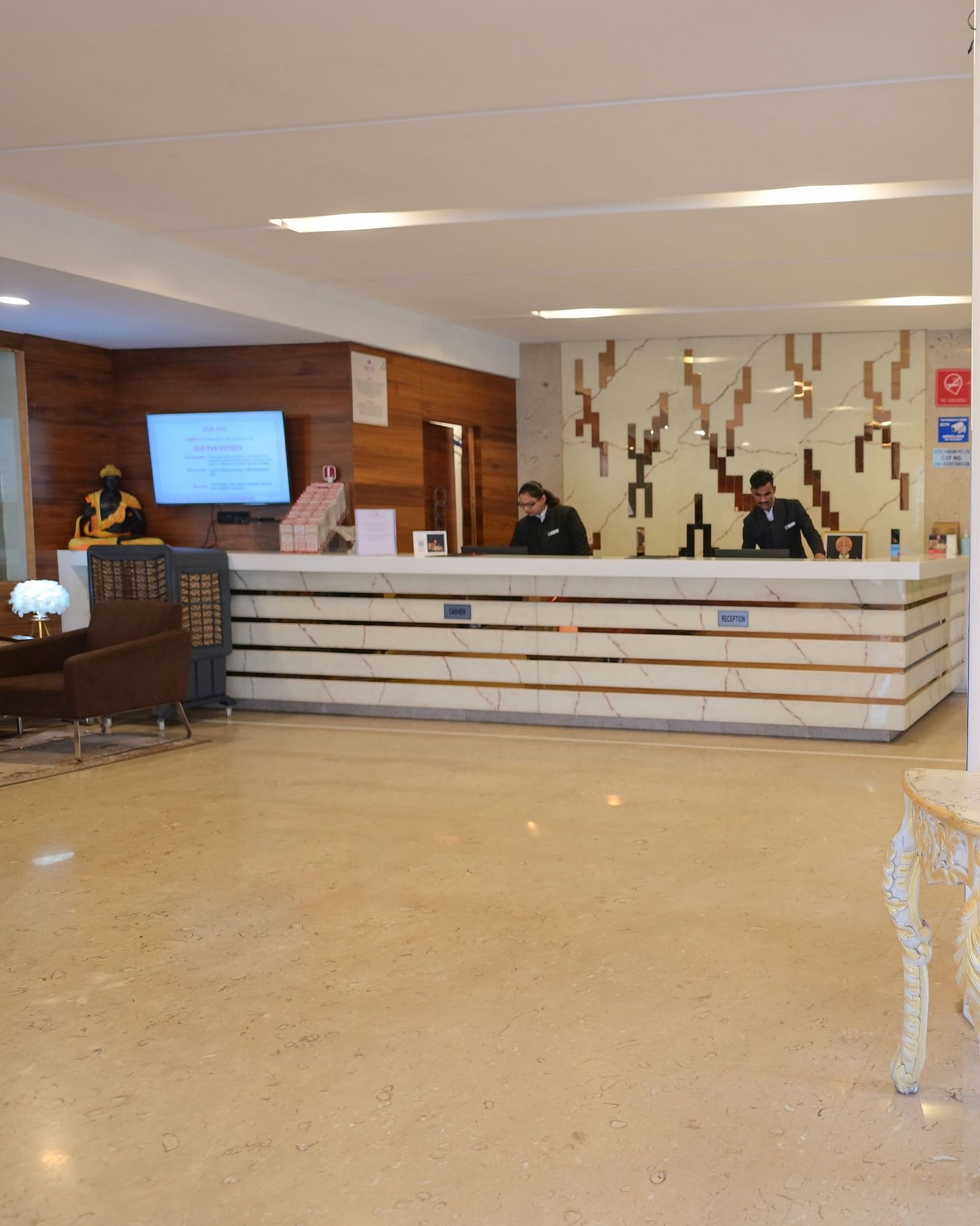 Hotel lobby interior with a decorative table, a statue of lords Ganesha, and a reception desk at Rang Lords Inn.