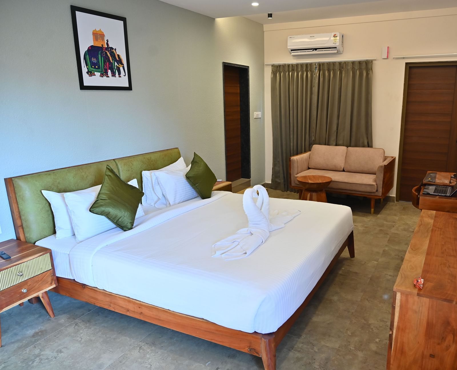 Spacious suite with a large bed, pillows, a sofa, and a wooden desk with modern amenities at TGI Livancia Hillside