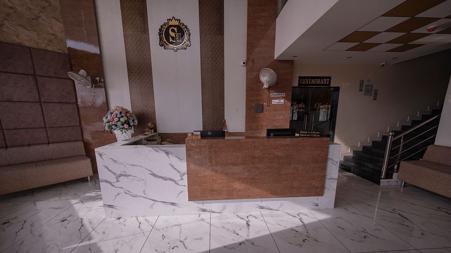 The reception area of Clarks Collection Somnath with marble desk, flower vase, soft seating, stairs, and modern interiors.
