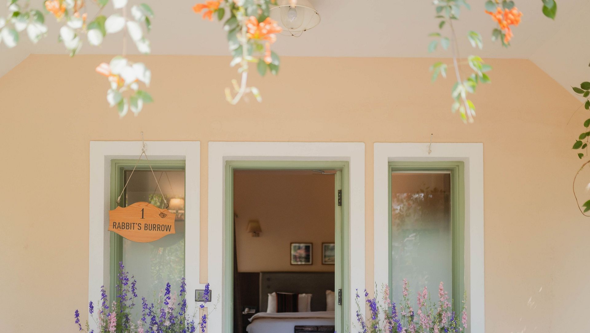 Exterior view of a Karma Chalets unit with two doors, potted plants, and hanging decor.